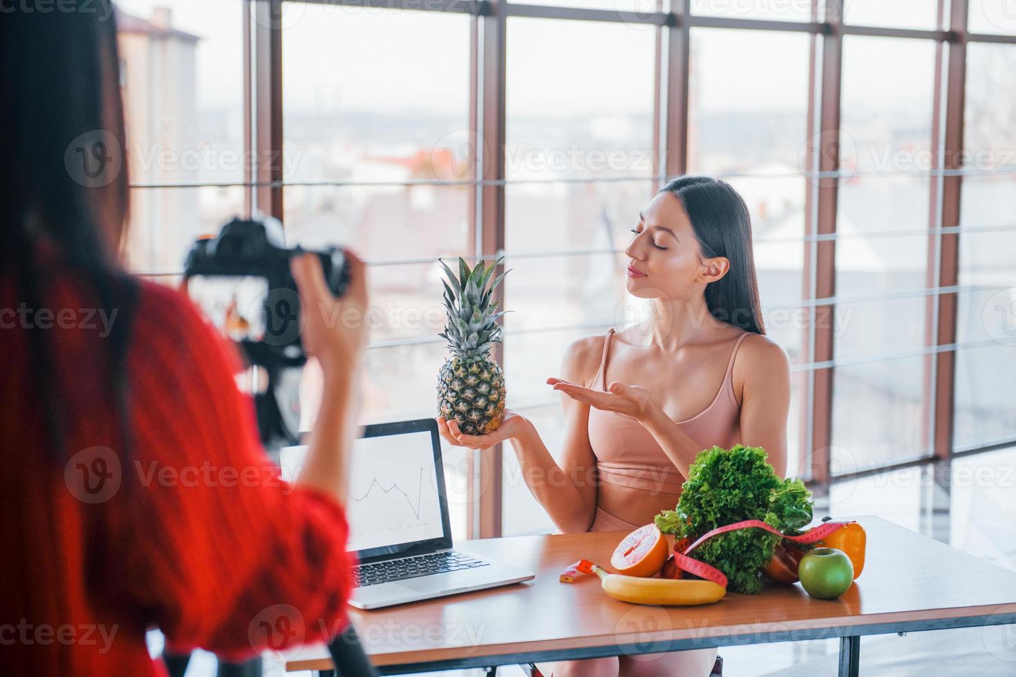 geschiktheid model- hebben fotoshoot door vrouw fotograaf binnenshuis door de tafel met gezond voedsel foto