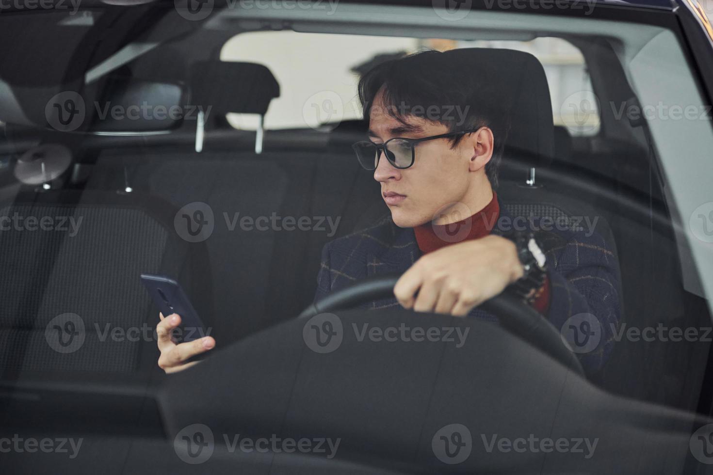 Mens in eyewear en formeel kleren zittend binnen van modern auto foto