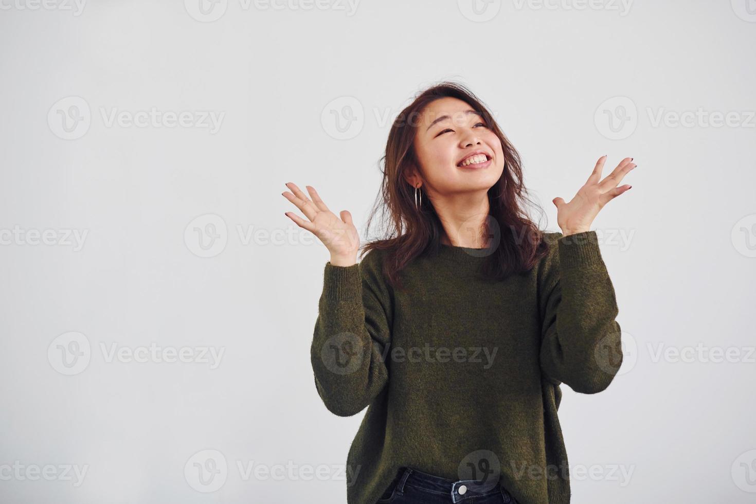 portret van gelukkig Aziatisch jong meisje dat staand binnenshuis in de studio tegen wit achtergrond foto