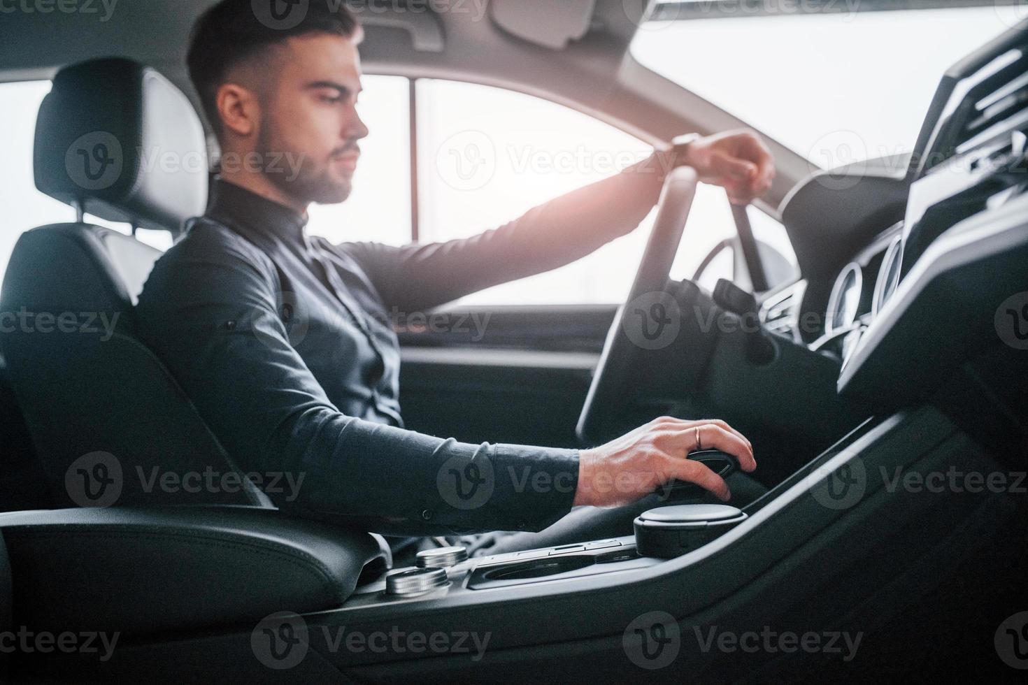 Mens in elegant kleren zittend in merk nieuw duur auto- foto