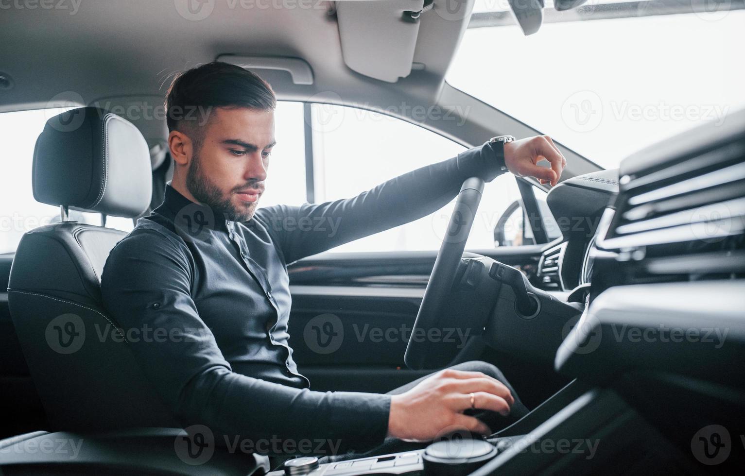 Mens in elegant kleren zittend in merk nieuw duur auto- foto