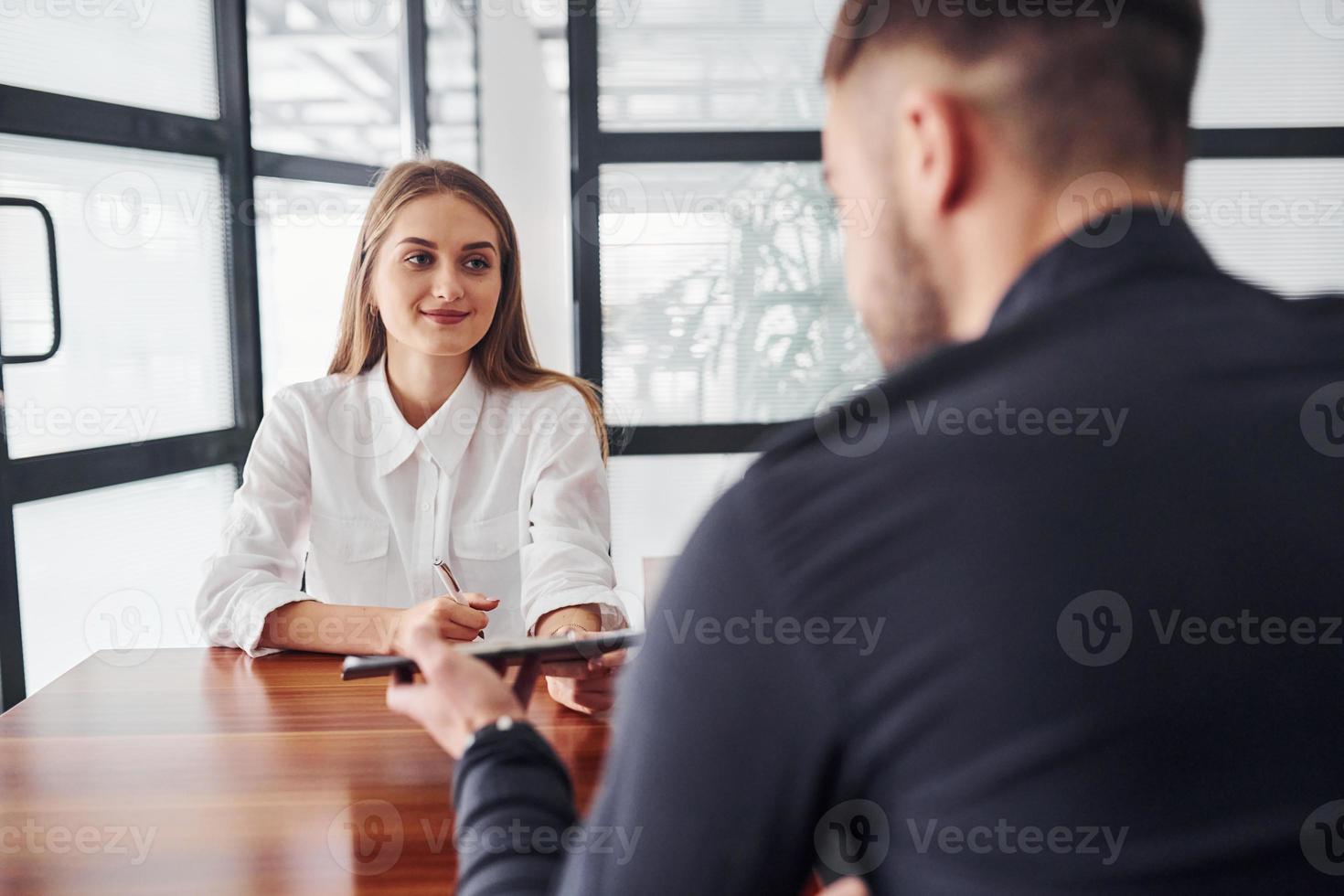 achterzijde visie. vrouw en Mens in formeel kleren werken samen binnenshuis in de kantoor door tafel foto