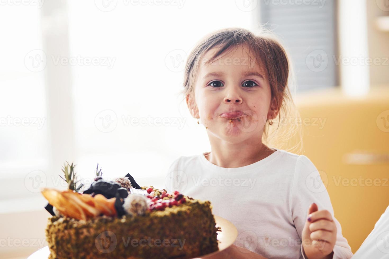 vrolijk weinig meisje aan het eten vers diëtisch taart Aan de keuken foto