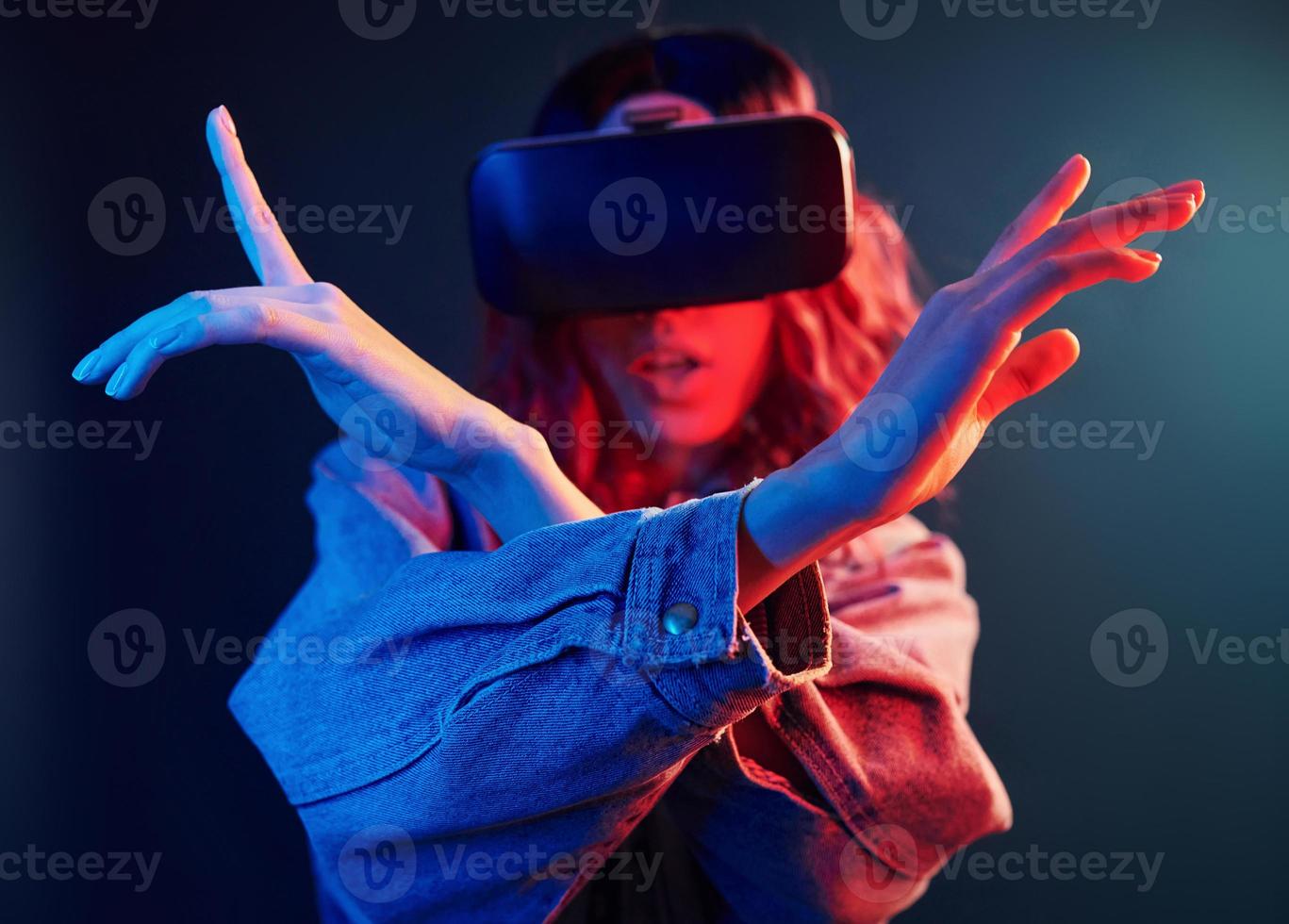 gelaats uitdrukking van jong meisje met virtueel realiteit bril Aan hoofd in rood en blauw neon in studio foto