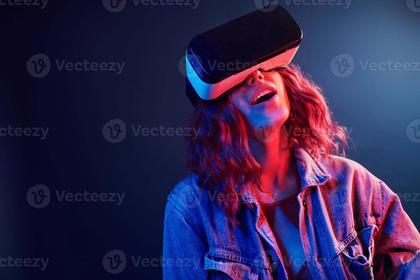 gelaats uitdrukking van jong meisje met virtueel realiteit bril Aan hoofd in rood en blauw neon in studio foto