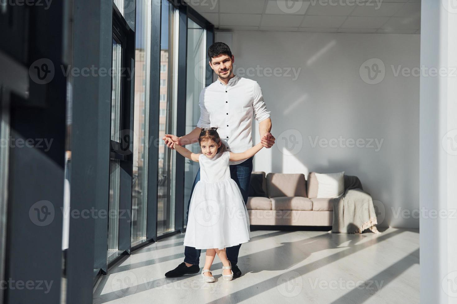 gelukkig vader met zijn dochter in jurk aan het leren hoe naar dans Bij huis samen foto
