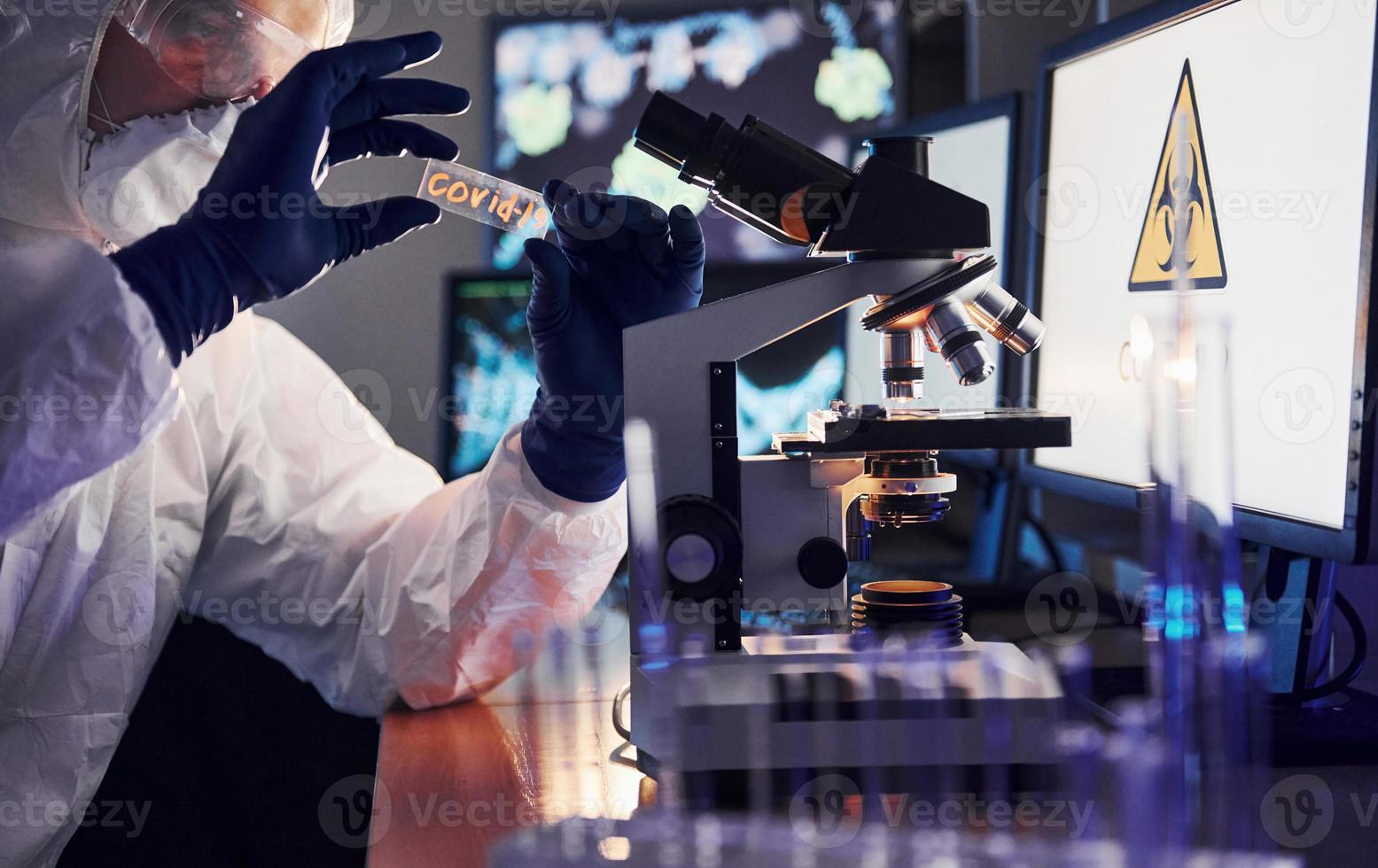 kant visie van wetenschapper in wit beschermend uniform dat werken met coronavirus in laboratorium foto