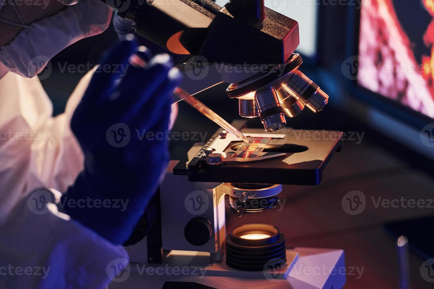 wetenschapper in wit beschermend uniform werken met coronavirus en bloed buizen in laboratorium foto