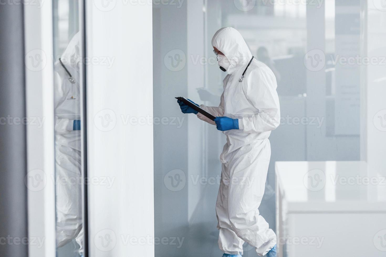 mannetje dokter wetenschapper in laboratorium jas, defensief eyewear en masker Holding kladblok in handen foto