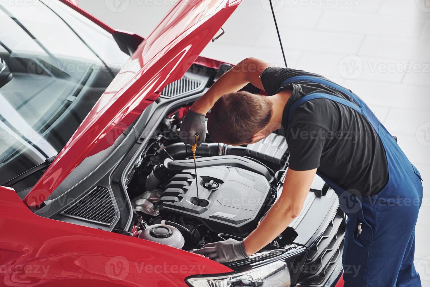 top visie van mannetje arbeider in uniform dat reparaties rood auto- foto