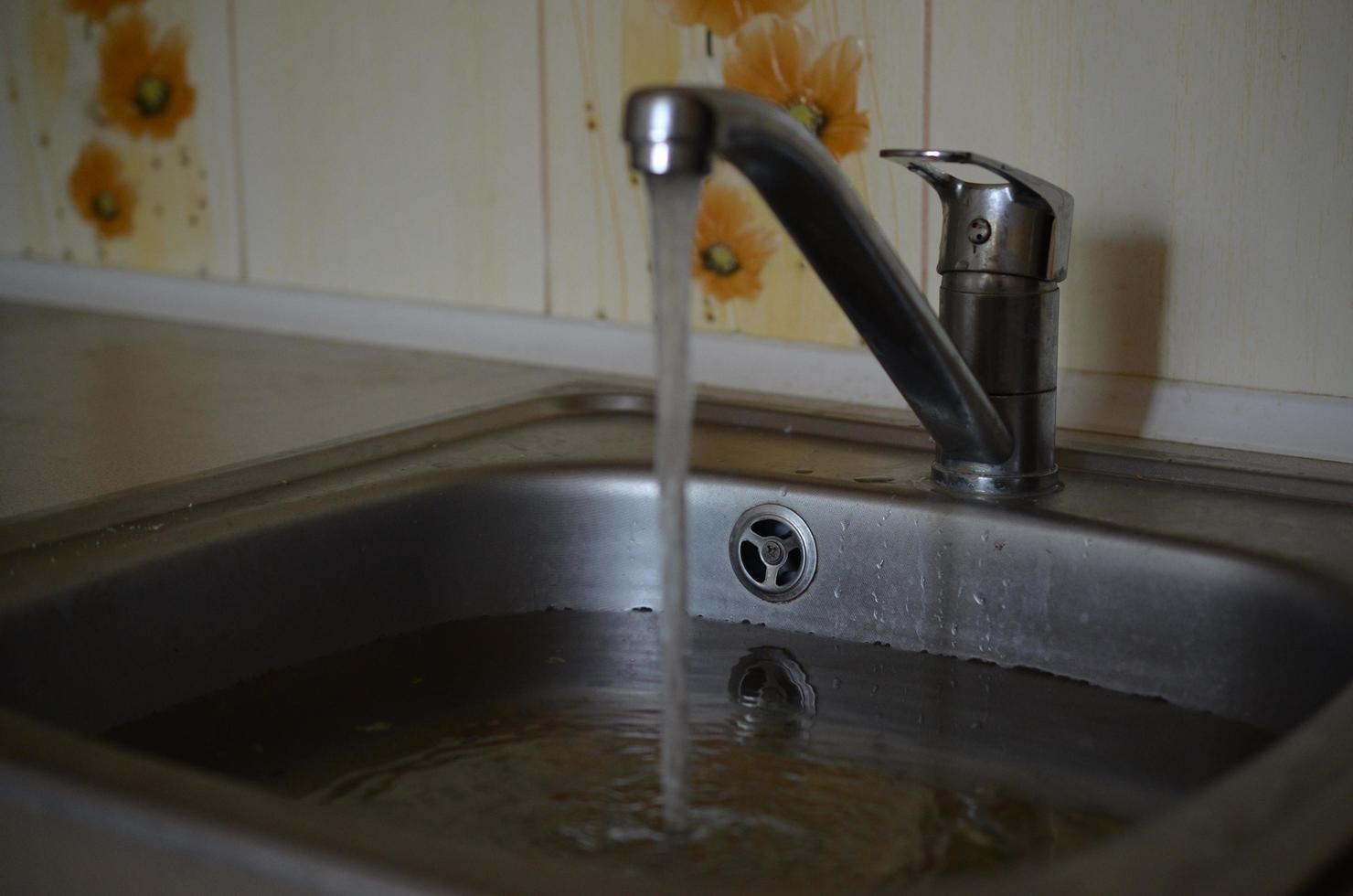 roestvrij staal wastafel plug gat dichtbij omhoog vol van water en deeltjes van voedsel foto