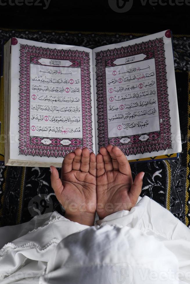 kind hand- bidden met verheven handen tegen de koran achtergrond. Islamitisch concept foto