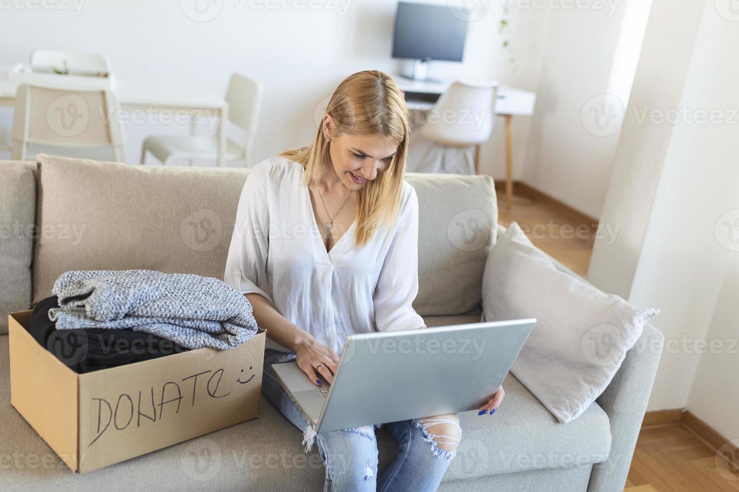 jong vrouw zittend Aan bankstel voorbereidingen treffen pakket voor Bezig met verzenden naar behoeftig menselijk. meisje met groot soort hart zet gebruikt kleren nieuw slijtage in bijdrage doos, concept van zorgzaam over dakloos mensen foto