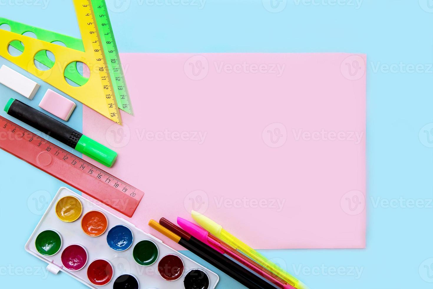 leeg roze vel Aan een blauw achtergrond omringd door school- accessoires - driehoeken, pennen, aquarellen, terug naar school- concept, school- achtergrond foto