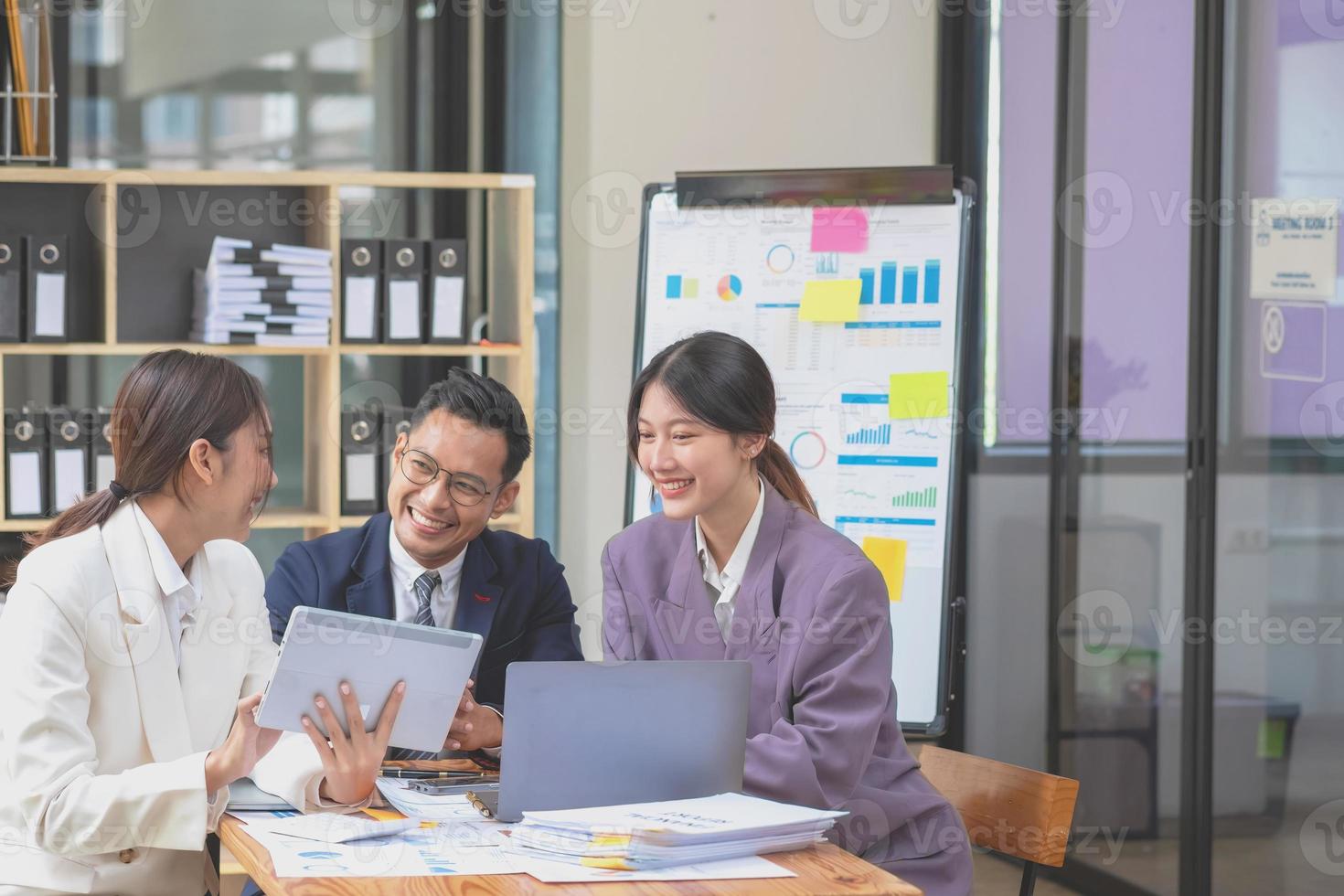 Aziatisch bedrijf team bestaat van afzet personeel. accountant en financieel officier helpen elk andere analyseren bedrijf winsten gebruik makend van tabletten. rekenmachine laptop computers, diagram papier, en zakelijke pennen. foto