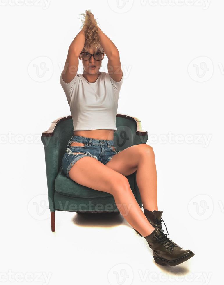 modieus elegant gek blond vrouw locatie in de stoel en poseren in voorkant van camera in studio. mode schoonheid concept. foto