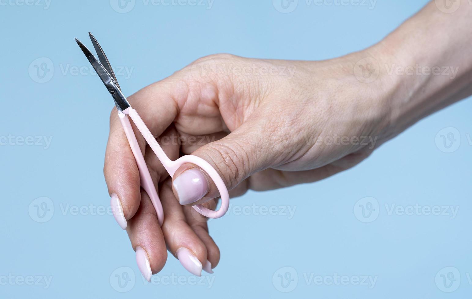 vrouw hand- Holding schaar geïsoleerd Aan blauw achtergrond foto