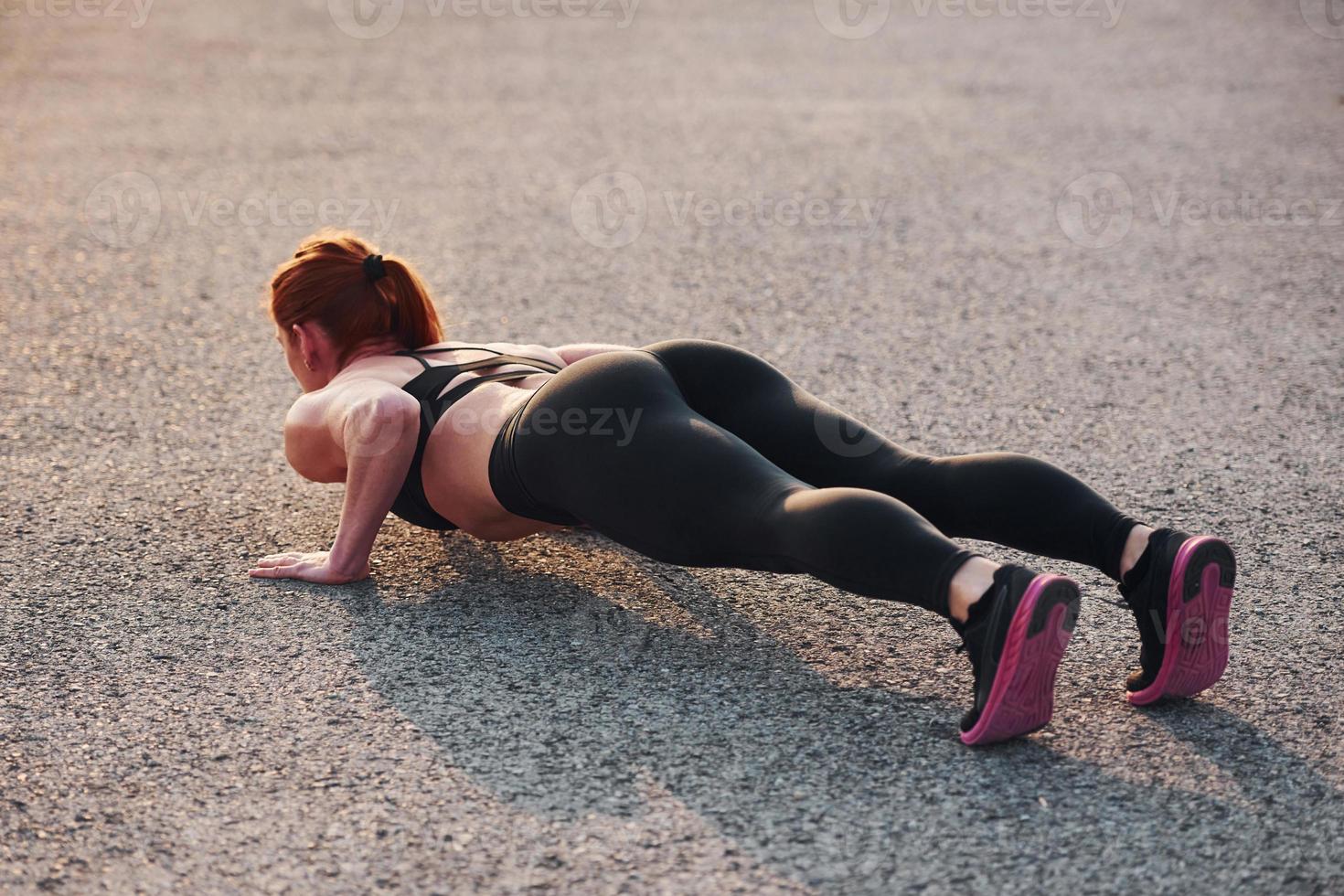 vrouw in sportkleding aan het doen Opdrukken Aan de weg Bij avond tijd foto