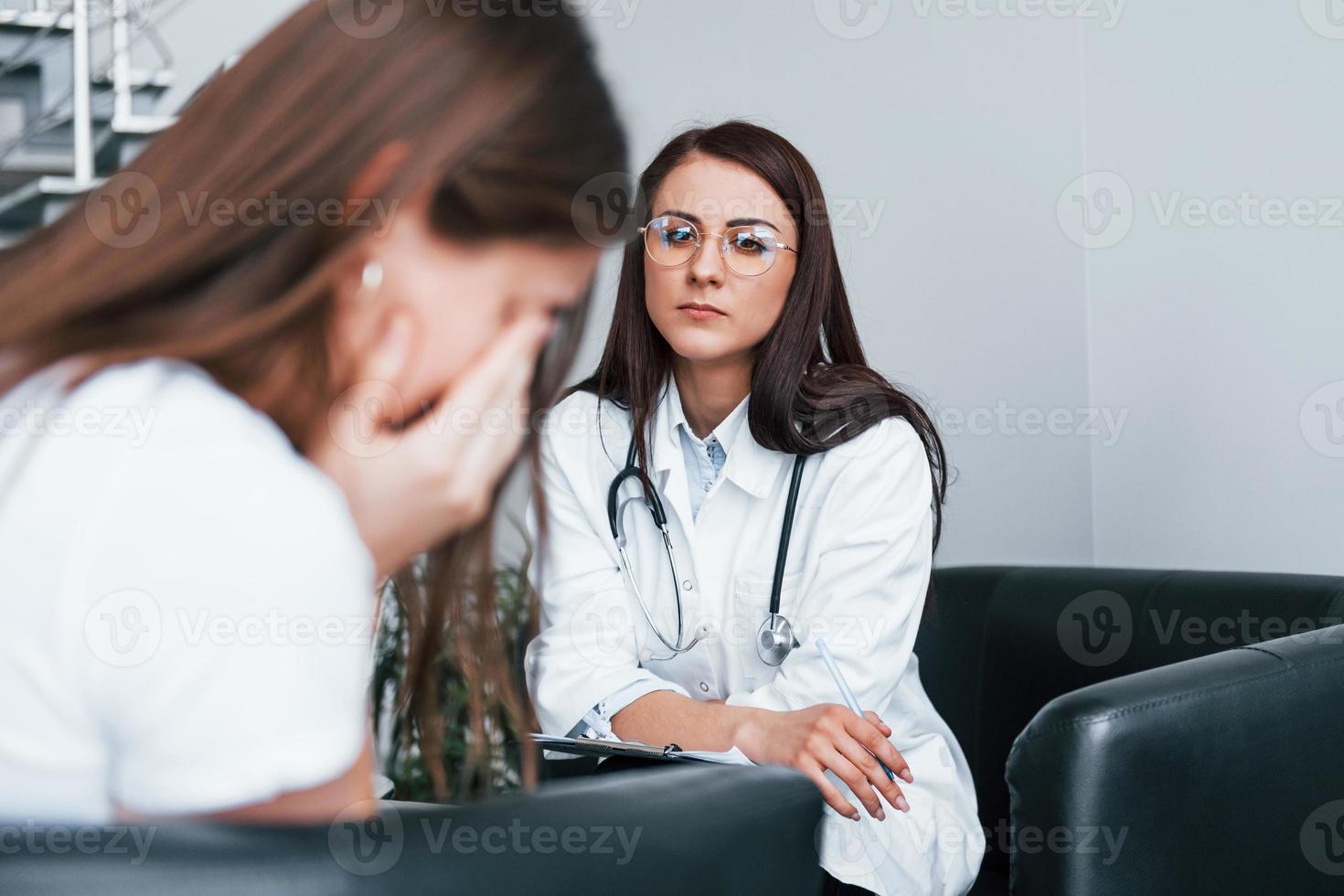 meisje hebben mentaal afbreken en huilen. jong vrouw hebben een bezoek met vrouw dokter in modern kliniek foto