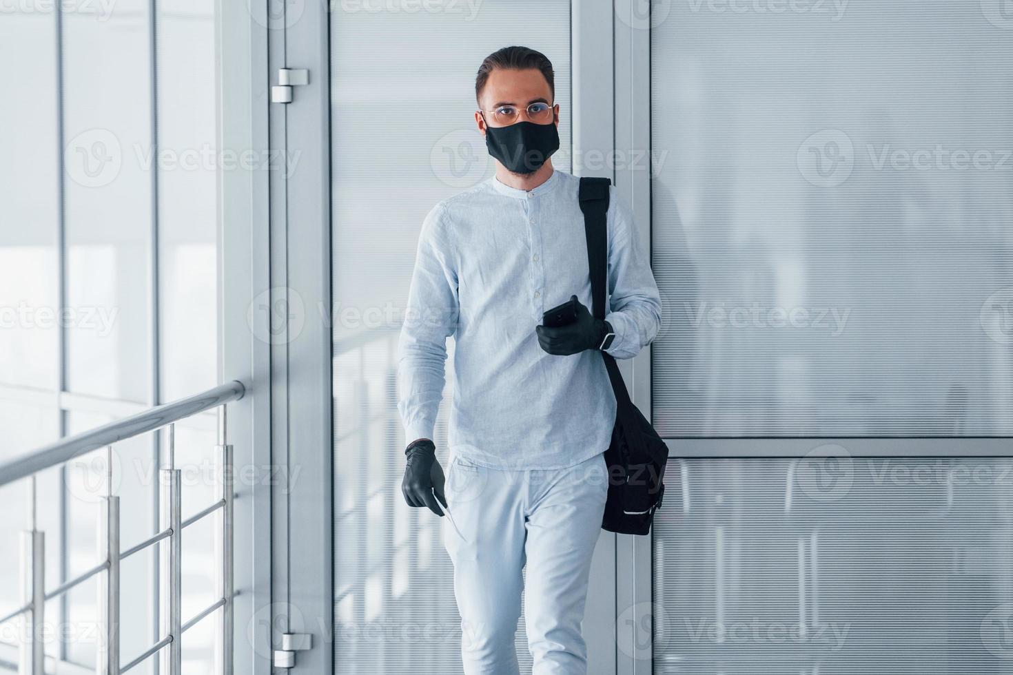 in beschermend masker en handschoenen. jong knap Mens in formeel kleren binnenshuis in de kantoor Bij dag foto