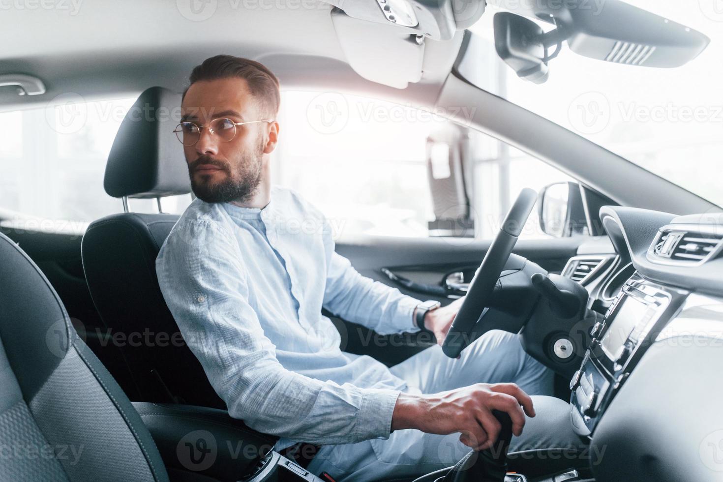 kant visie van jong knap Mens in formeel kleren dat zittend in merk nieuw auto- foto