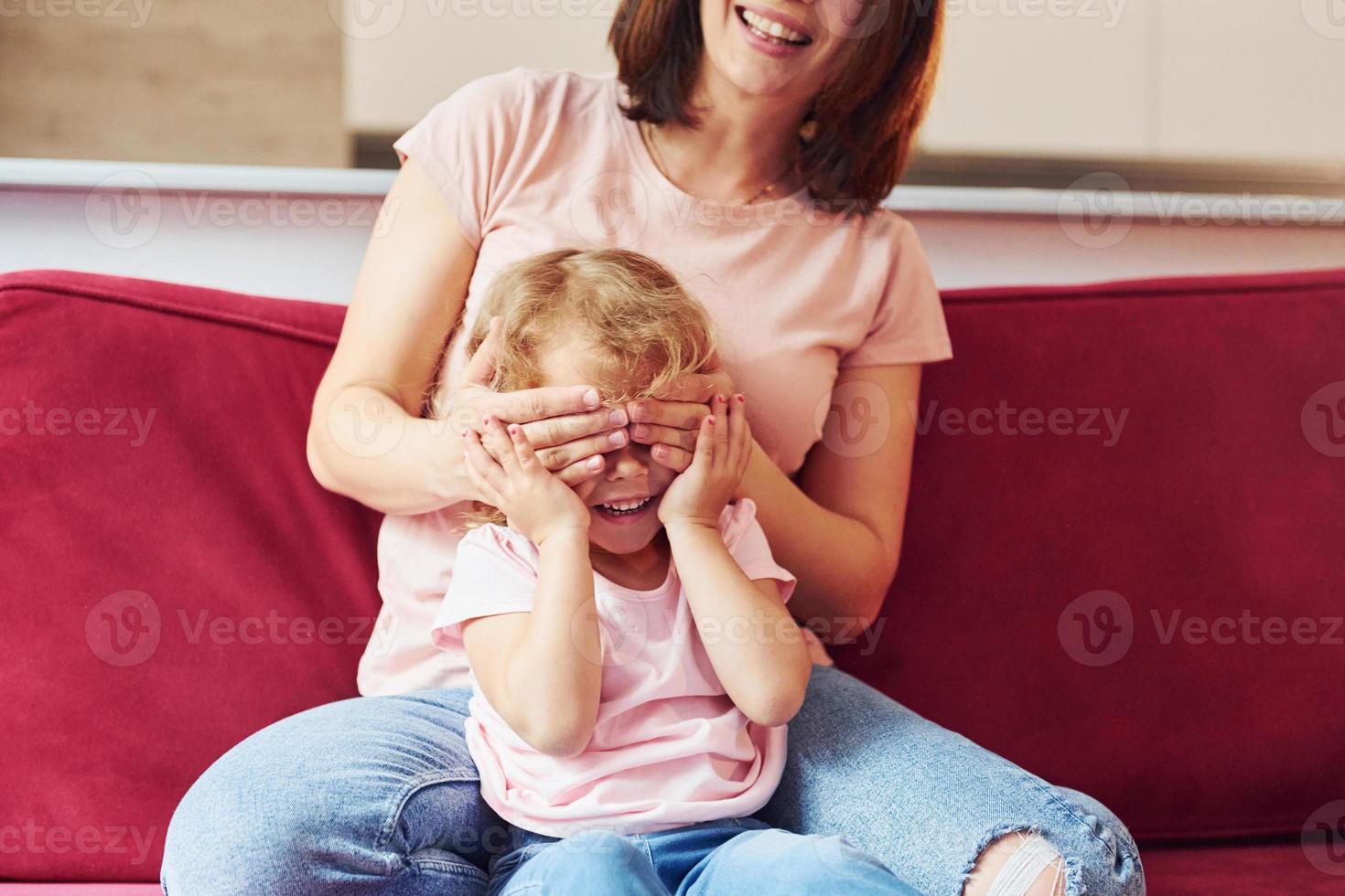 jong moeder met haar weinig dochter in gewoontjes kleren samen binnenshuis Bij huis foto