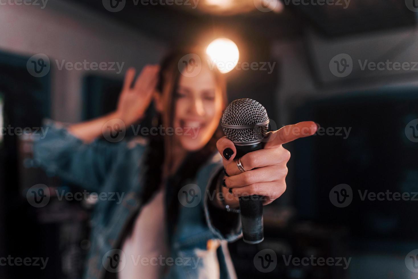 dichtbij omhoog visie van microfoon. jong mooi vrouw performer repeteren in een opname studio foto