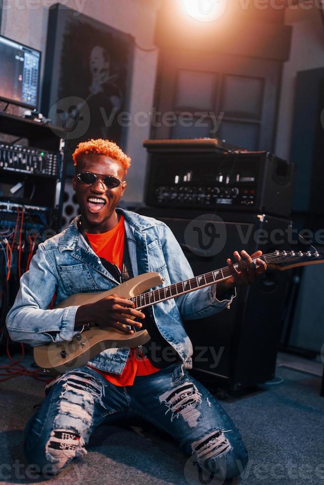 Toneelstukken gitaar. jong Afrikaanse Amerikaans performer repeteren in een opname studio foto