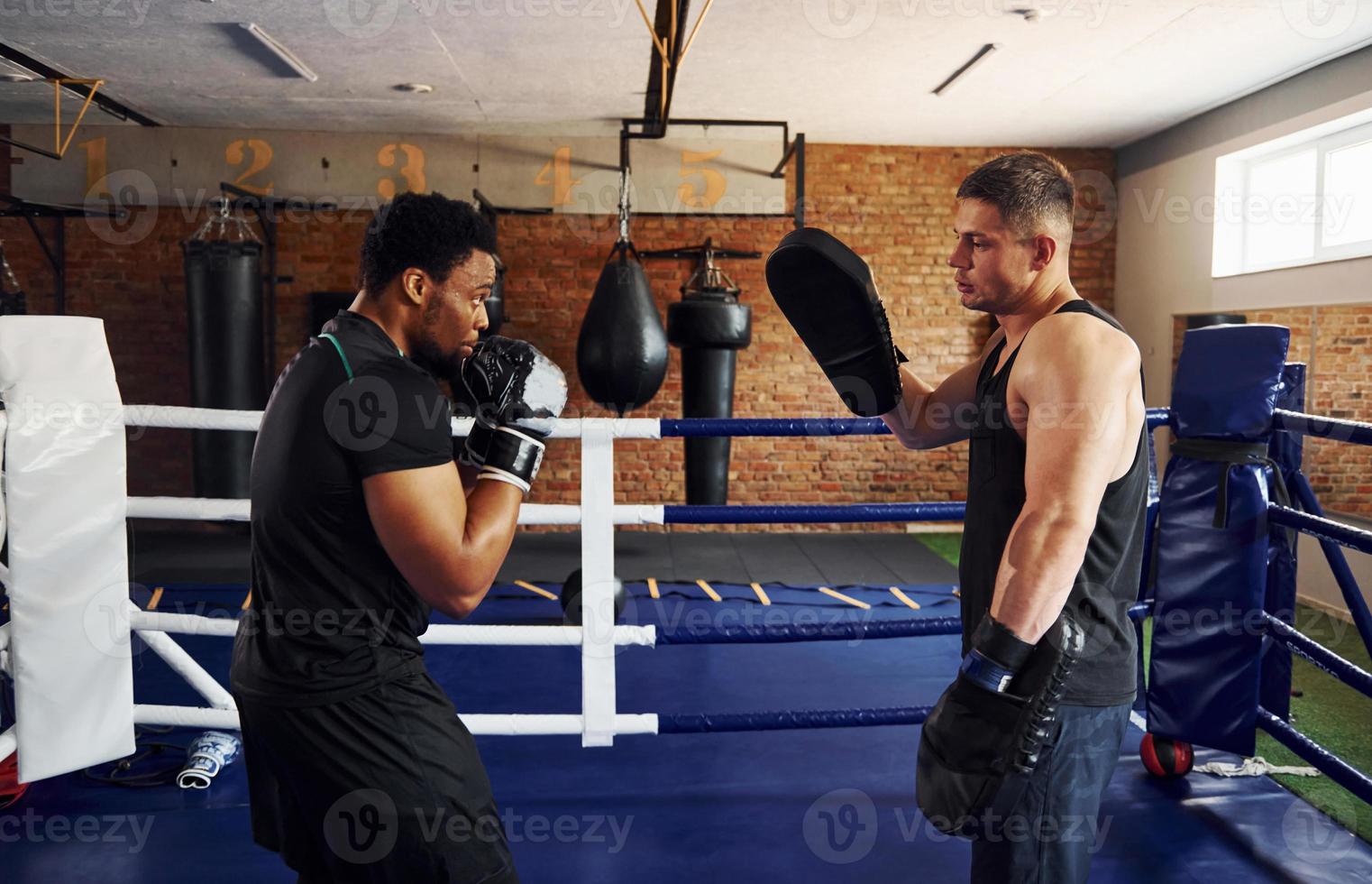 hebben boksen praktisch. Afrikaanse Amerikaans Mens met wit vent hebben training dag in Sportschool foto