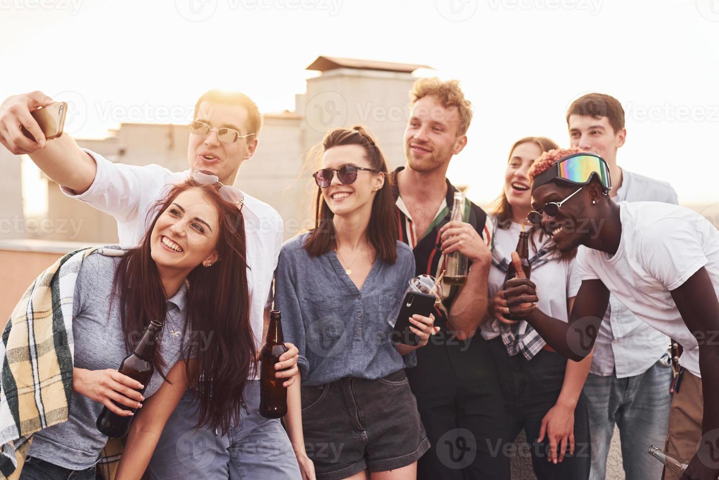 maken selfie door telefoon. groep van jong mensen in gewoontjes kleren hebben een partij Bij op het dak samen Bij dag foto