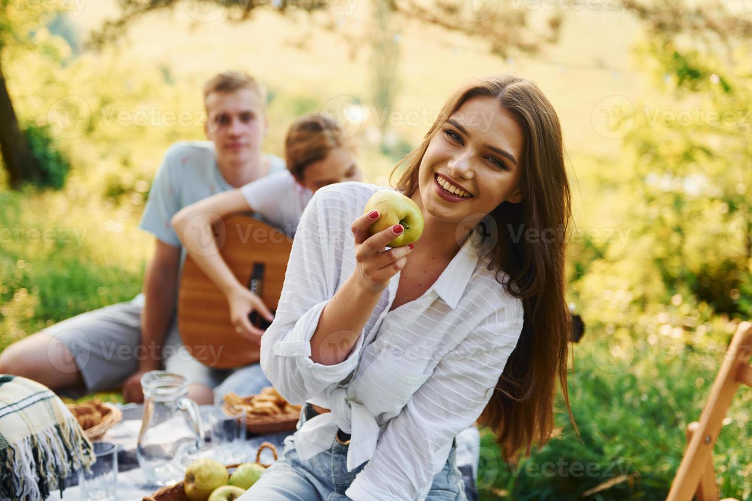 vrouw eet appel. groep van jong mensen hebben vakantie buitenshuis in de Woud. opvatting van weekend en vriendschap foto