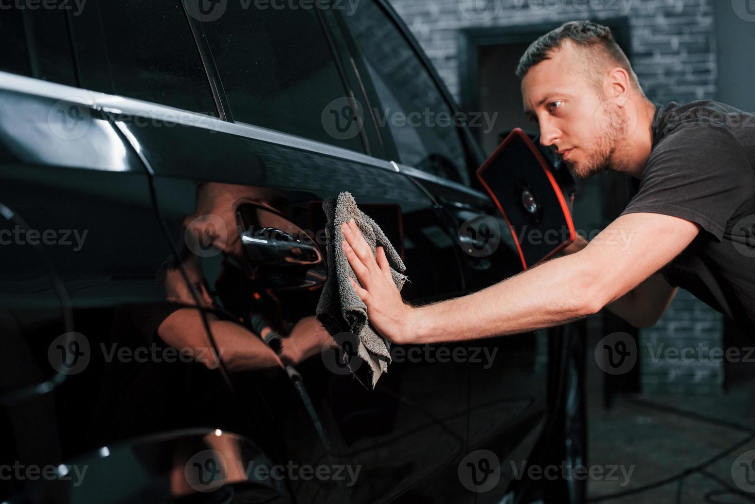 modern zwart auto- krijgen schoongemaakt door Mens binnen van auto wassen station foto