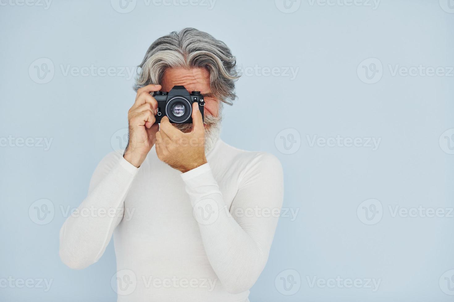 fotograaf met wijnoogst camera. senior elegant modern Mens met grijs haar- en baard binnenshuis foto