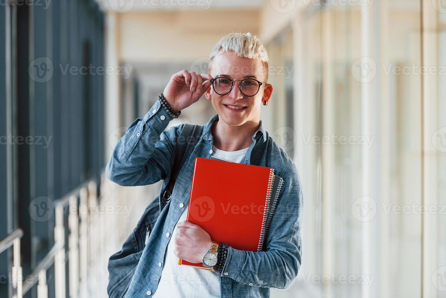 mannetje jong leerling in jeans kleren is in gang van een college met kladblok in handen foto