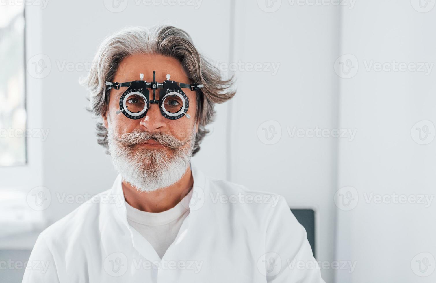 senior Mens met grijs haar- en baard is in oogheelkunde kliniek foto