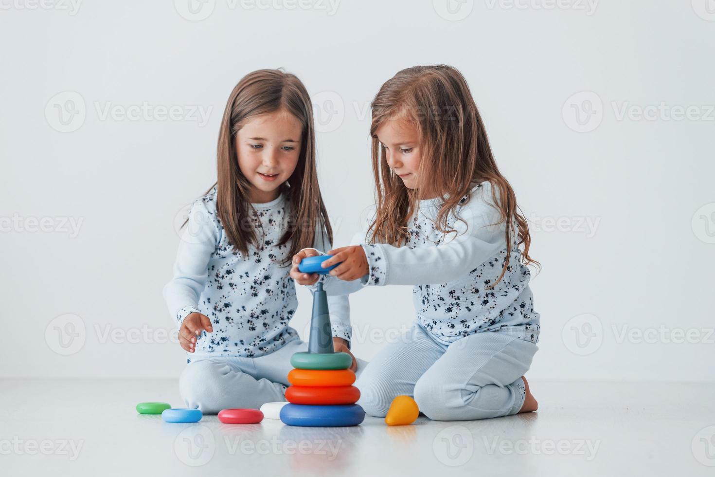 spelen met speelgoed. twee schattig weinig meisjes binnenshuis Bij huis samen. kinderen hebben pret foto