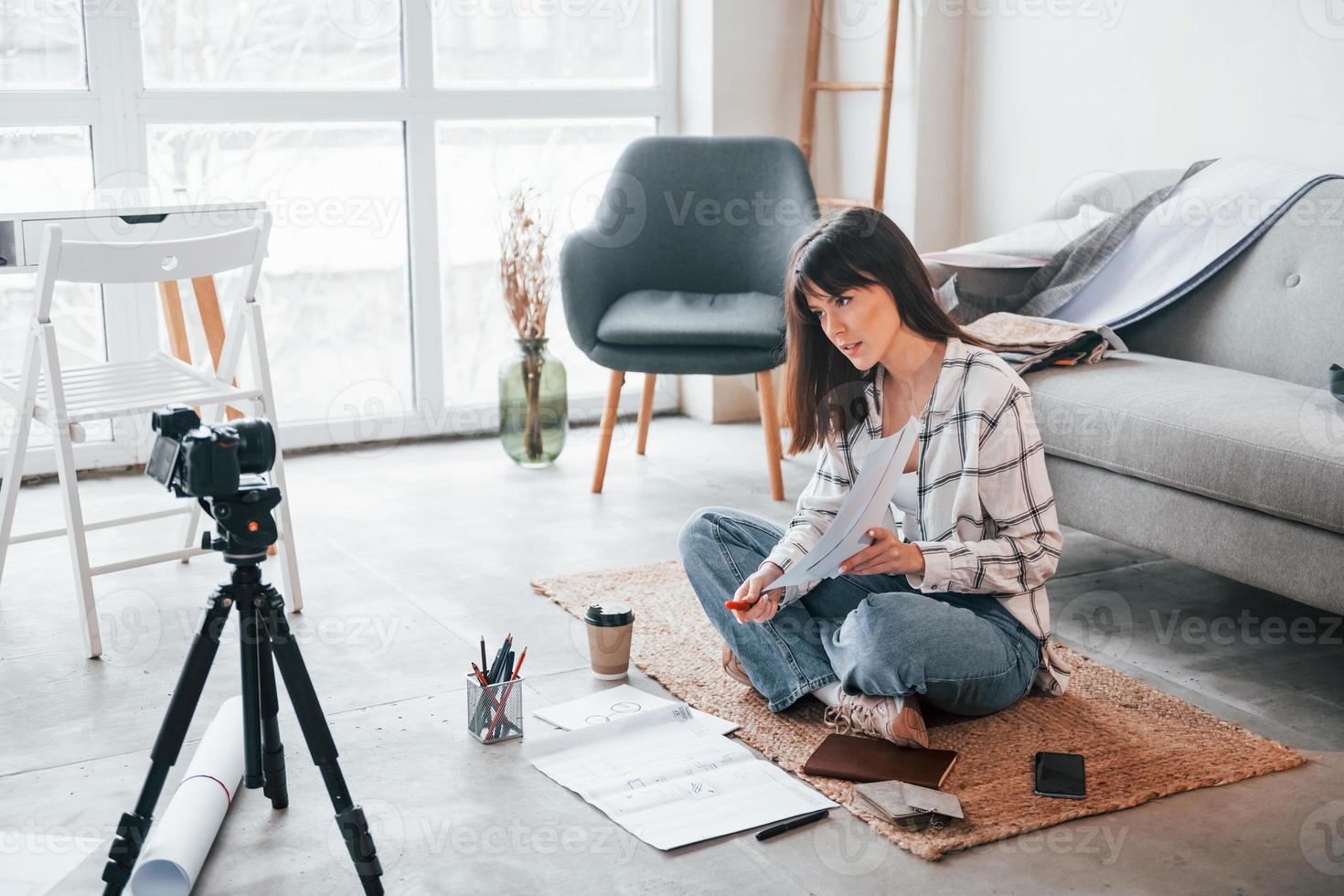 maakt inhoud voor bloggen. camera Aan de vloer. jong vrouw freelance arbeider is binnenshuis in huis Bij dag foto