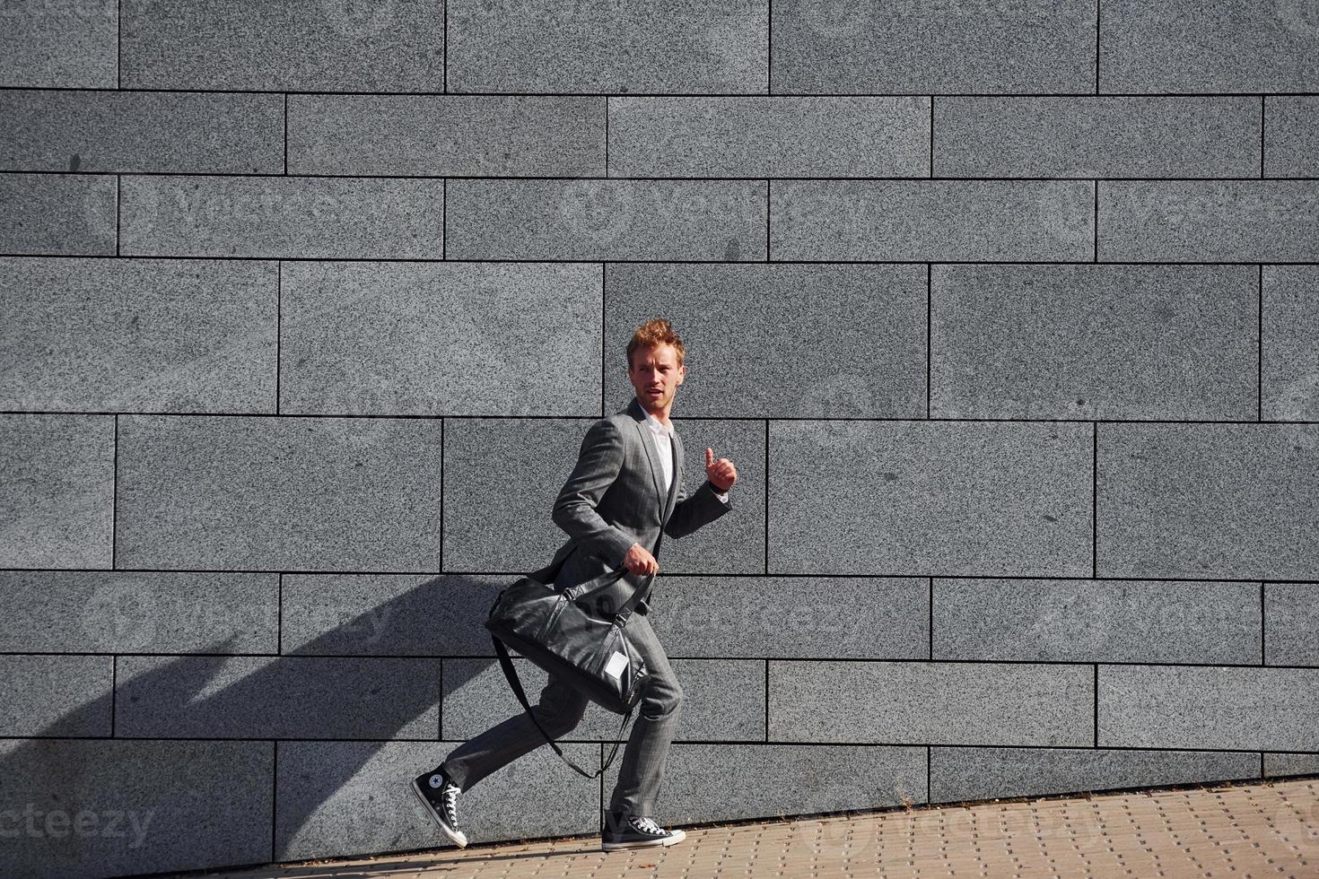 loopt en latijn naar de functie. jong zakenman in grijs formeel slijtage is buitenshuis in de stad foto