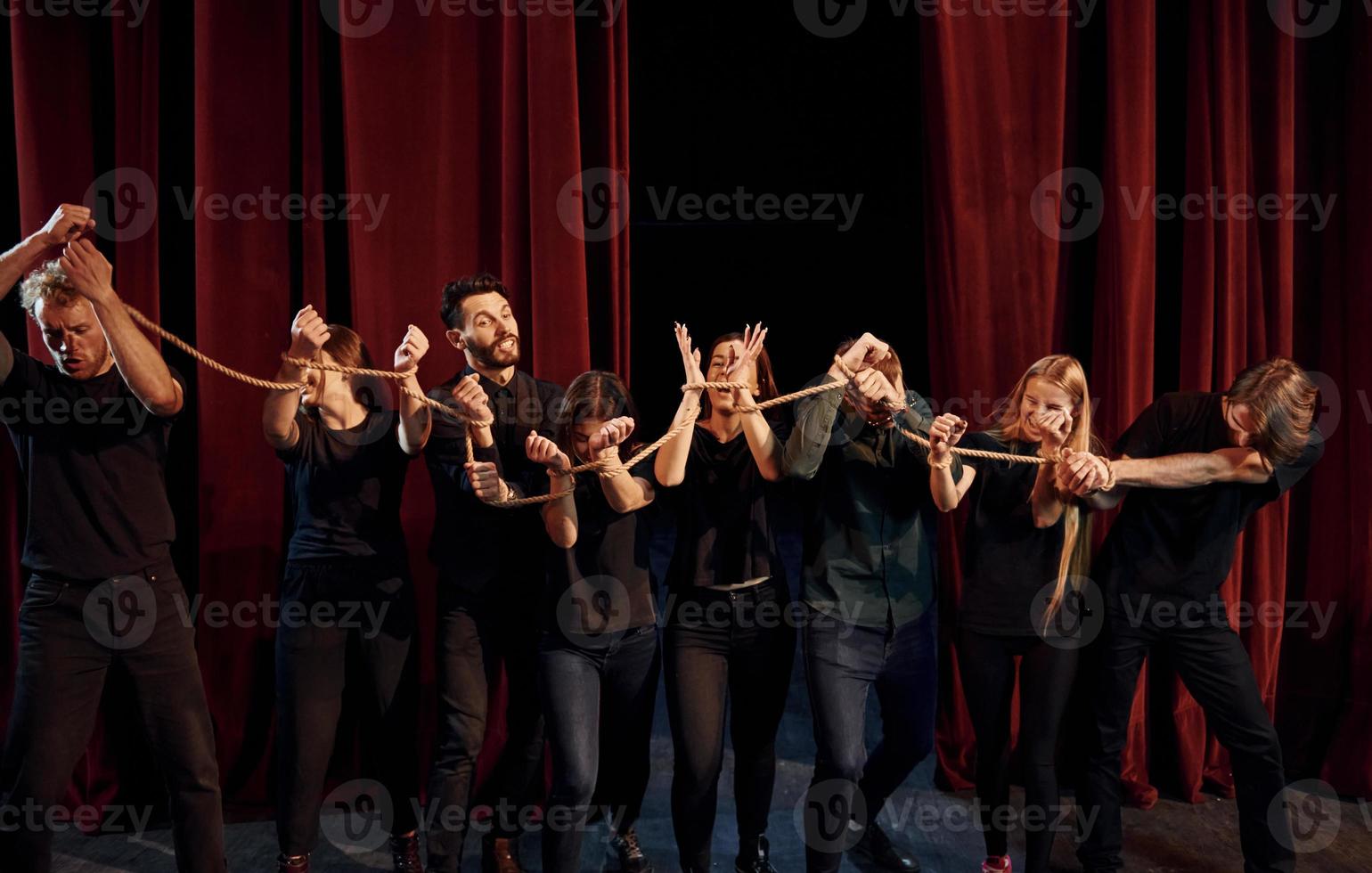 knoop in de handen. groep van acteurs in donker gekleurde kleren Aan repetitie in de theater foto