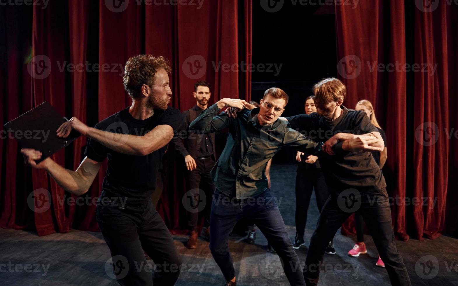 strijd tafereel. groep van acteurs in donker gekleurde kleren Aan repetitie in de theater foto