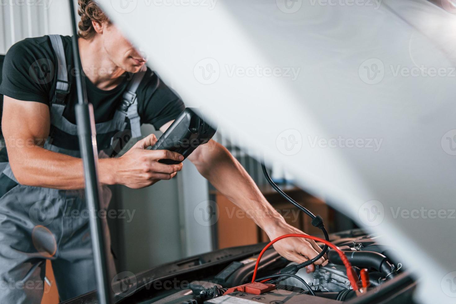 tests auto's elektronica. volwassen Mens in grijs gekleurde uniform werken in de auto- salon foto