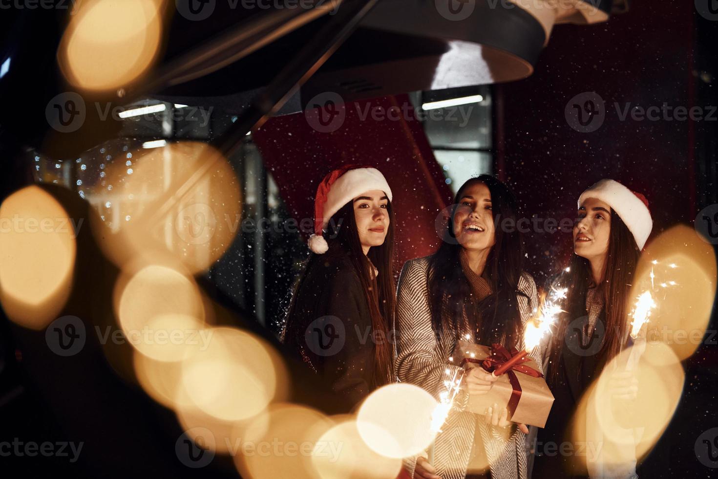 weinig vuurwerk, Bengalen lichten. drie vrolijk Dames besteedt Kerstmis vakantie samen buitenshuis. opvatting van nieuw jaar foto