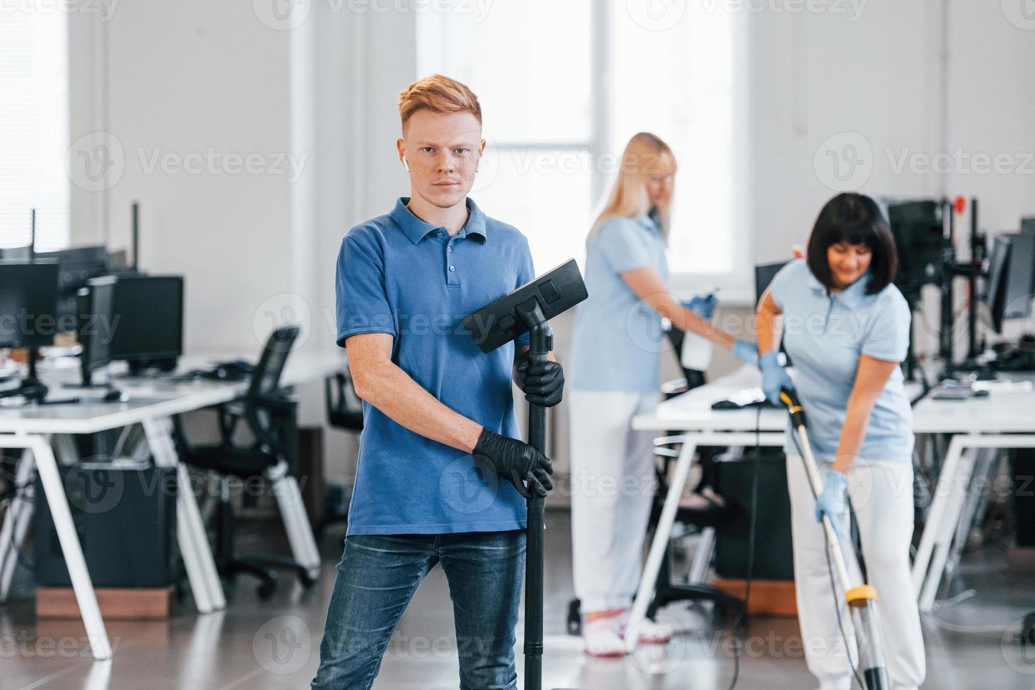 vent met vacuüm schoner. groep van arbeiders schoon modern kantoor samen Bij dag foto