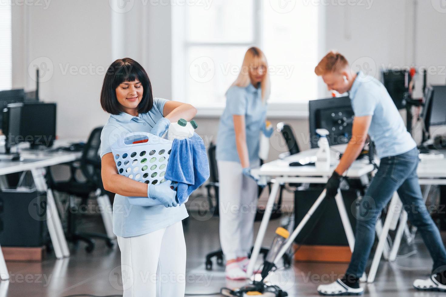 vrouw met mand. groep van arbeiders schoon modern kantoor samen Bij dag foto