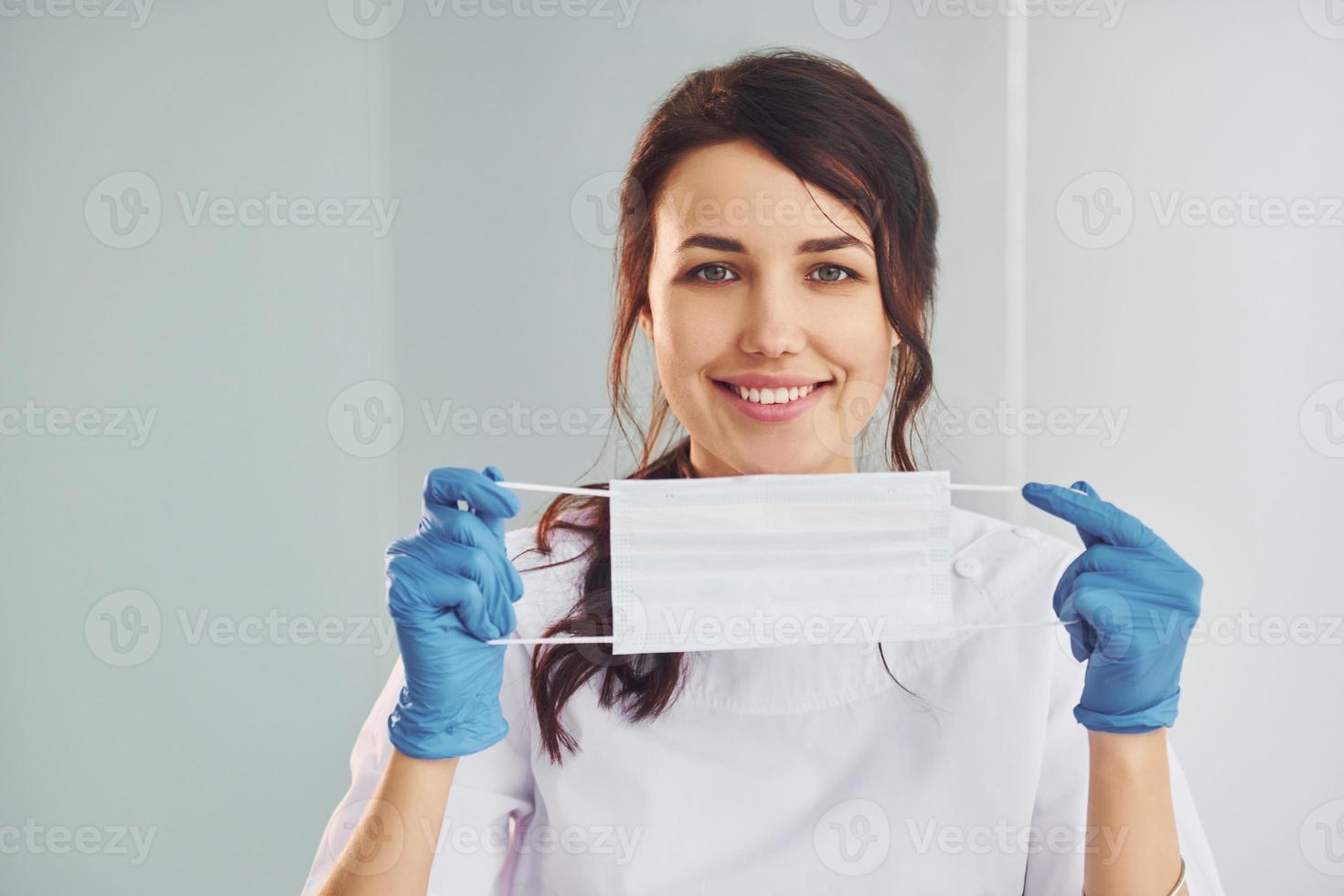 medisch masker. portret van professioneel vrouw tandarts met uitrusting dat staand binnenshuis foto