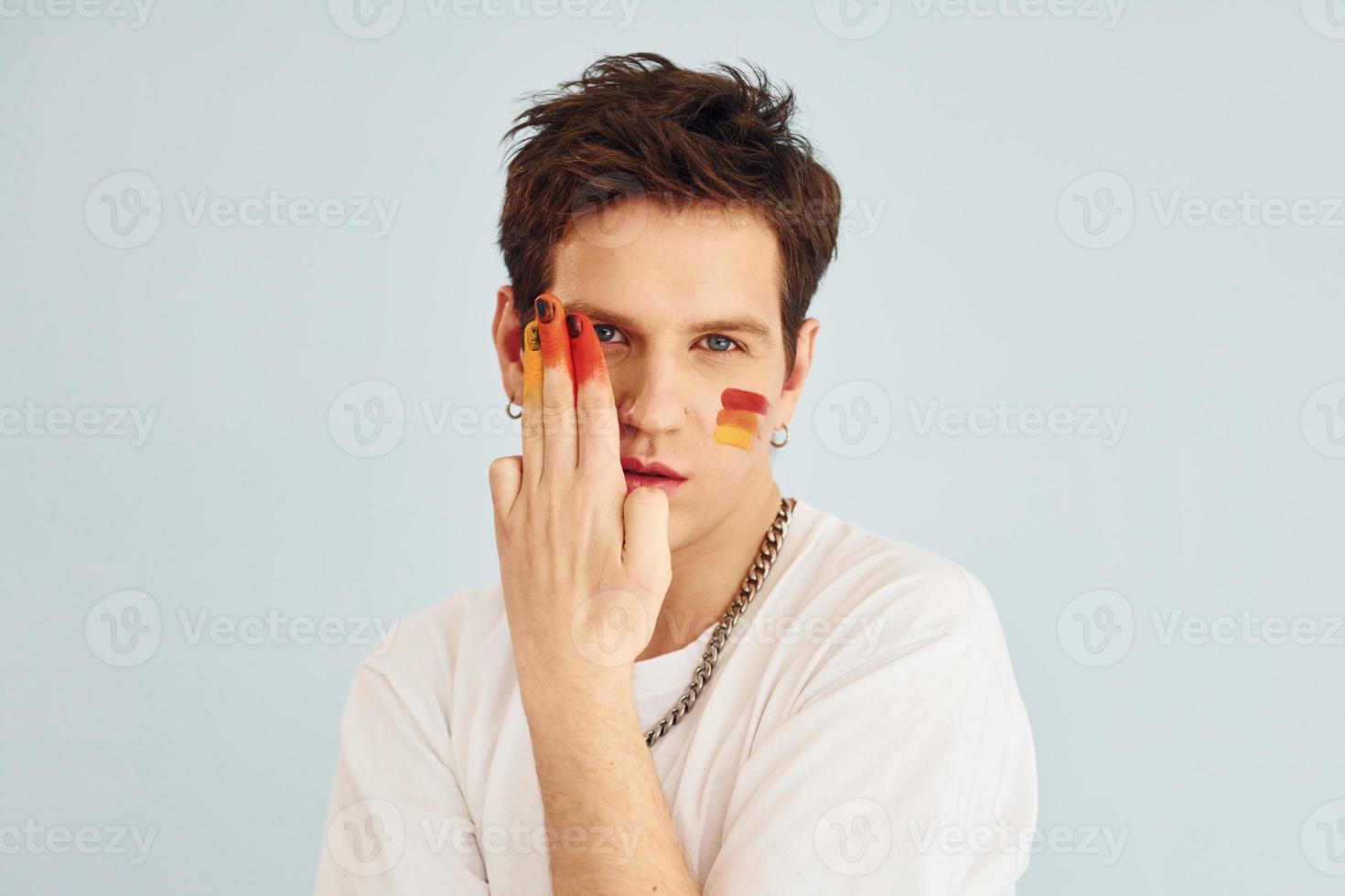 jong homo Mens is staand in de studio en poseren voor een camera. geschilderd door multi gekleurde bedenken foto