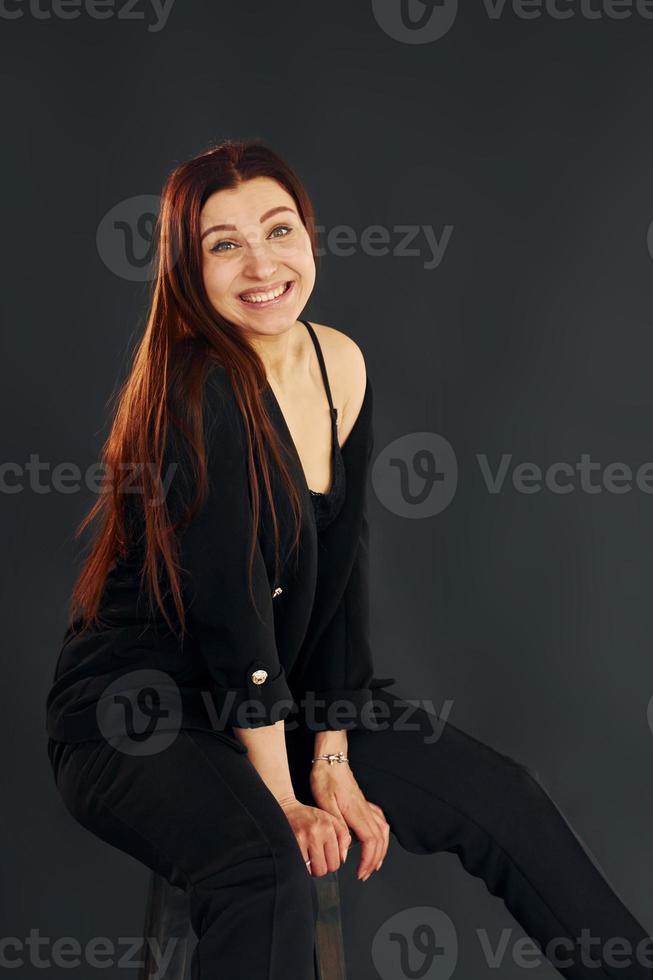 vrouw in zwart kleren is poseren voor de camera binnenshuis in de studio foto