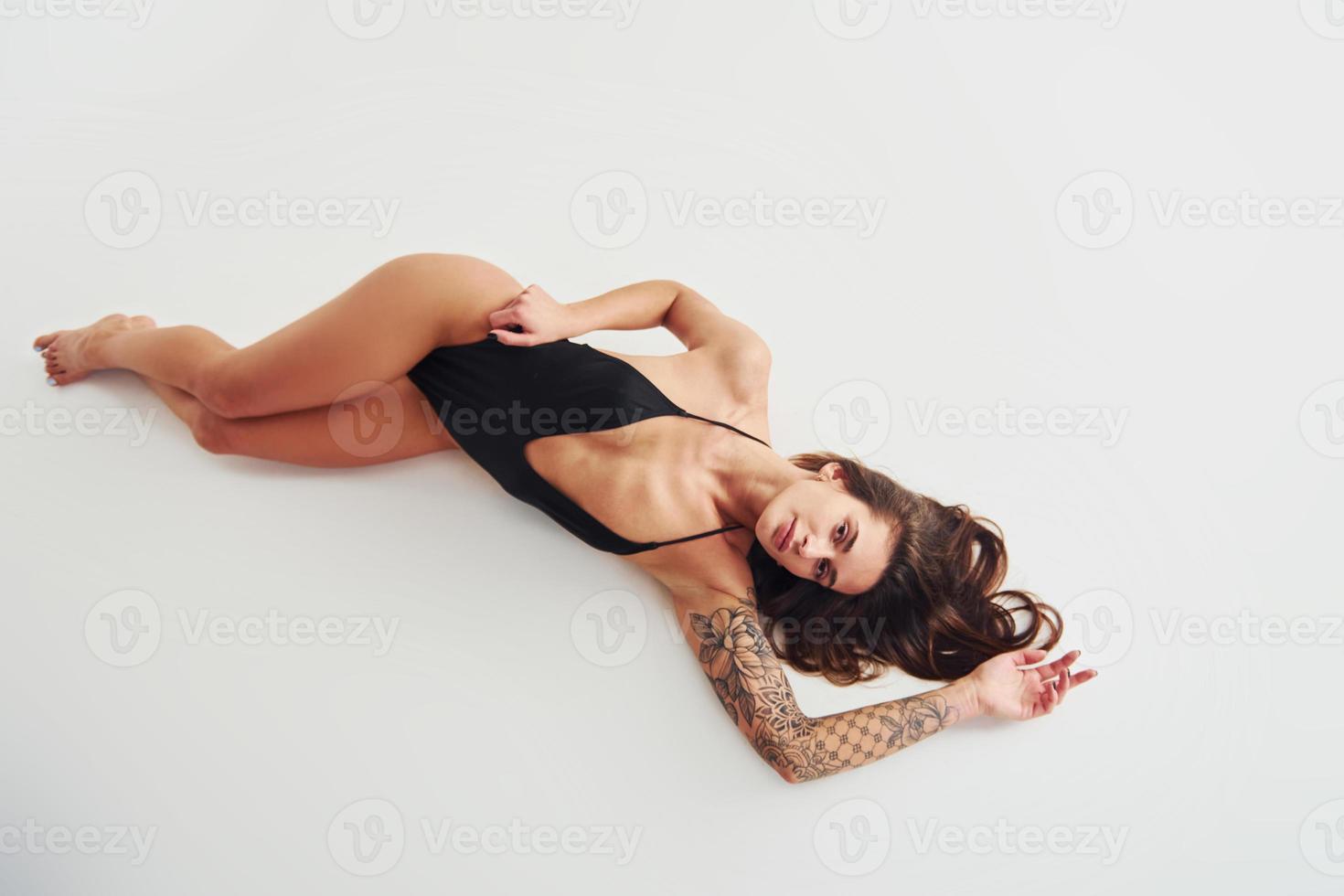 aan het liegen naar beneden Aan de grond. mooi verleidelijk sportief vrouw met sexy lichaam is poseren in de studio foto