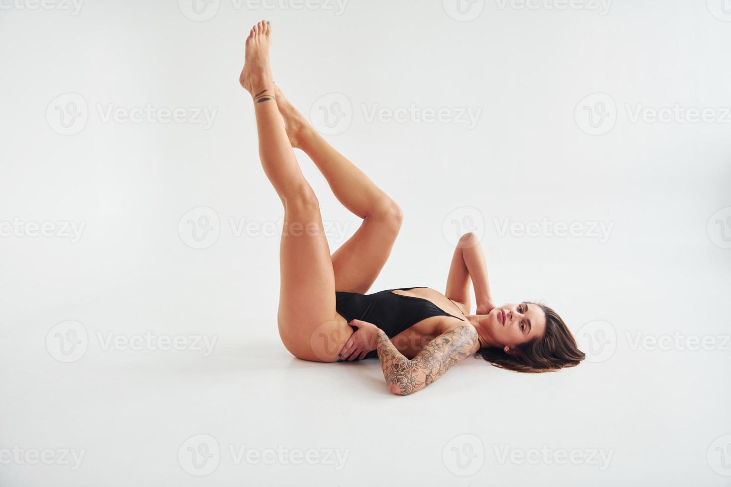 aan het liegen naar beneden Aan de grond. mooi verleidelijk sportief vrouw met sexy lichaam is poseren in de studio foto