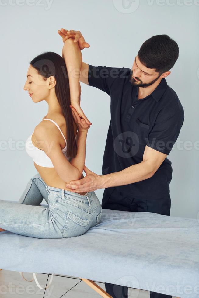 meisje is zitten. fysiotherapeut werken met jong vrouw binnenshuis in de spa foto